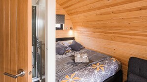 Un dormitorio acogedor con techo de madera, cama con ropa de cama estampada y una mesita de noche.