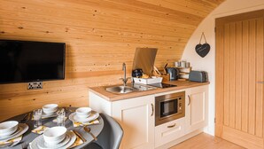 Cocina compacta con techo de madera, televisor de pantalla plana, microondas y un lavamanos.