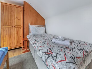 A bedroom with a bed, a wooden wardrobe, and a small wooden stool. - 20 Blackbird Cottage-UK38935 (Lands End, near Porthcurno)