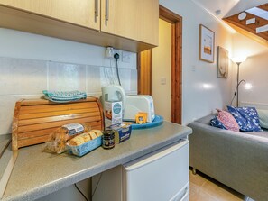 A kitchen with a toaster, bread, a kettle, and a coffee maker on the counter.