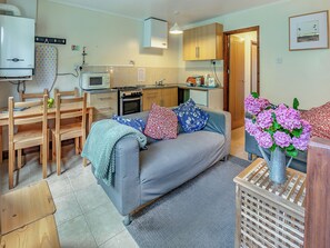 A compact living space with a kitchenette, a dining area, and a sofa with multiple cushions.