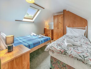 Un dormitorio con dos camas, un tragaluz, muebles de madera y un escritorio con lámpara.