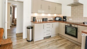Une cuisine moderne avec des armoires de couleur beige, une hotte en acier inoxydable, un four encastré et un plan de travail en bois.