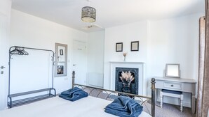 Une chambre à coucher avec un grand lit, une commode, un miroir, un radiateur et une cheminée.