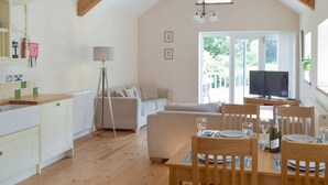 A spacious living area with a dining table set for two, a sofa, and a television. - Troed Y Rhiw Aberpoth (Aberporth)