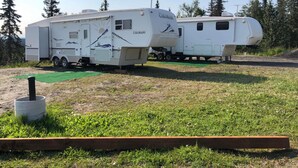 Twee witte campers staan op een grasveld met een groene mat ervoor.