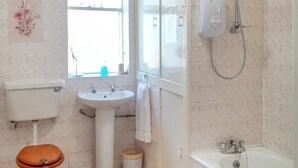 Een badkamer met toilet, wastafel, douche en raam.