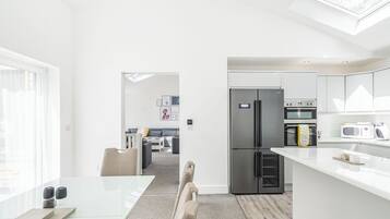 A modern kitchen with a built-in fridge, oven, and microwave, a dining area with a table and chairs, and a living room with a sofa and a coffee table.