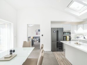 A modern kitchen with a built-in fridge, oven, and microwave, a dining area with a table and chairs, and a living room with a sofa and a coffee table.