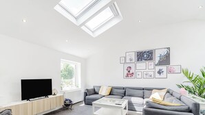 A modern living room with a grey sofa set, a flat-screen TV, a coffee table, and a skylight. - We love how modern and stylish High Trees View is. (Knaresborough, near Harrogate)