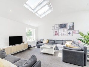 A modern living room with a grey sofa set, a flat-screen TV, a coffee table, and a skylight. - We love how modern and stylish High Trees View is. (Knaresborough, near Harrogate)