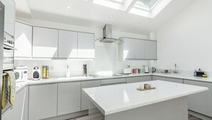 A modern kitchen with skylights, white cabinetry, and a central island. - We love how modern and stylish High Trees View is. (Knaresborough, near Harrogate)