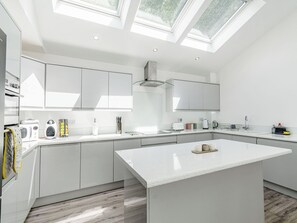 Una cocina moderna con tragaluces, armarios blancos y una isla central.