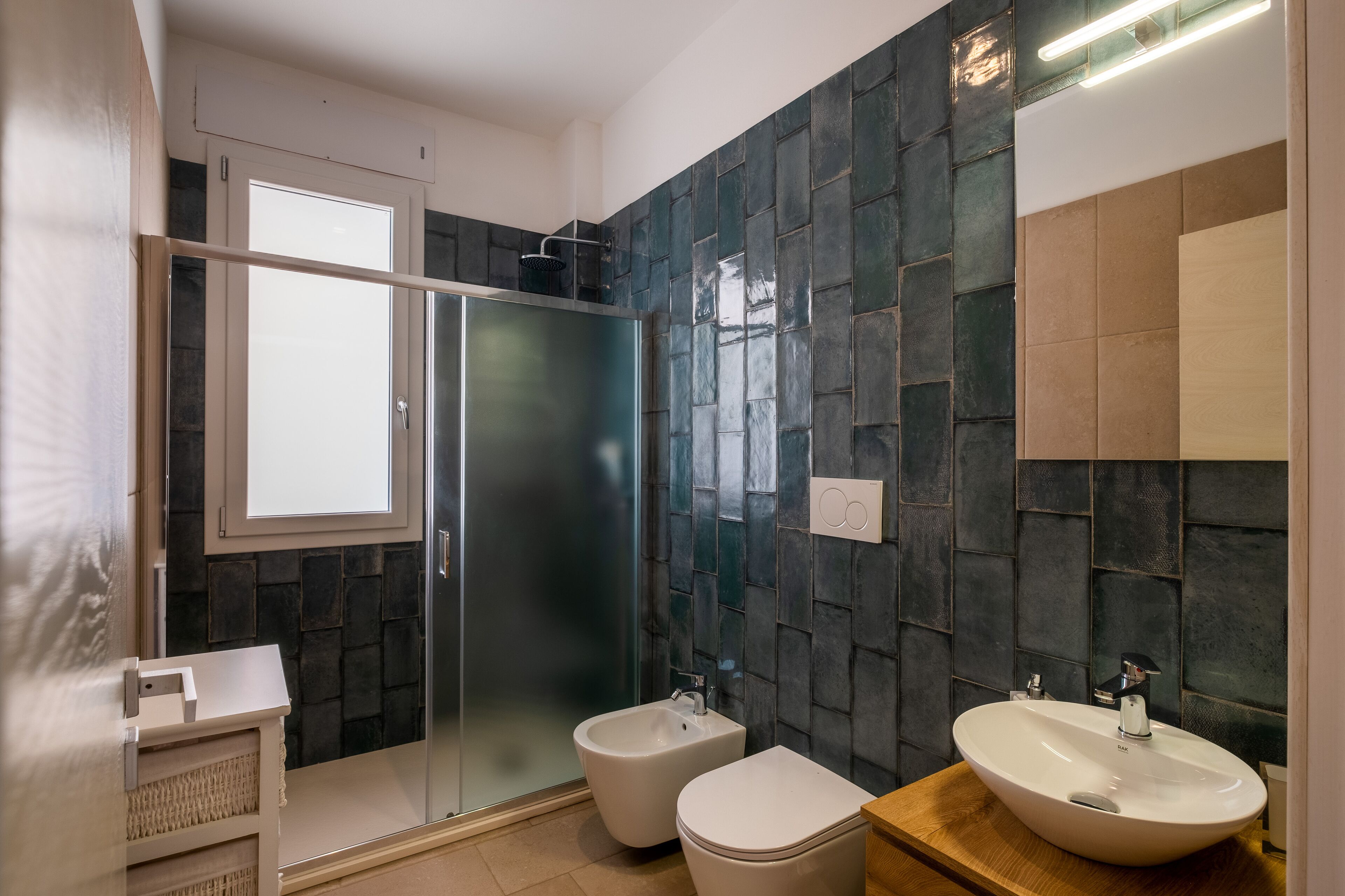 Un baño moderno con cabina de ducha de vidrio, un bidé, un inodoro y un lavabo.