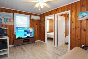 Cozy retreat with a flat-screen TV, comfortable bed, and a door leading to an adjacent room.