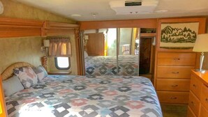 Een slaapkamer met een bed, een dressoir, een spiegel en een raam.