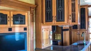 Een kleine keuken met houten kastjes, een ingebouwde televisie en een plafondventilator.