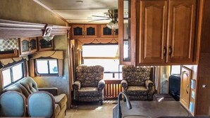 Een compact RV-interieur met een kitchenette, zithoek en een klein raam.