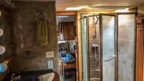Een ruimtelijk RV-badkamer met een douchecabine, een wastafel en een klein opbergmeubel.