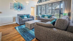 Un salon moderne avec deux canapés, une table basse et une grande fenêtre donnant sur l’extérieur.