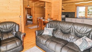 Ein gemütliches Blockhaus-Interieur mit Ledersofa, Esstisch und Küchenzeile.