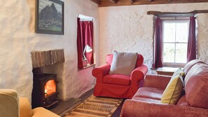 A cozy living room with a fireplace, red furniture, and a painting on the wall.