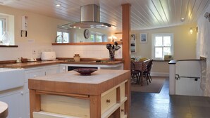 A modern kitchen with a central island, wooden cabinets, and a built-in stove.