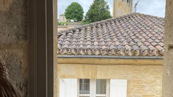 A window with a view of a building with a tiled roof and stone walls.
