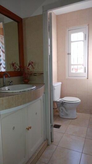 A bathroom with a sink, mirror, toilet, and a window. - Caminito en Planta Alta (Salta)