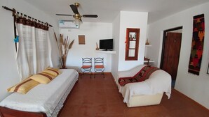 A room with two beds, a ceiling fan, a TV, and a door with a mirror. - Caminito en Planta Alta (Salta)