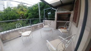 A balcony with two white metal chairs and a small round table, surrounded by a metal railing. - Caminito en Planta Alta (Salta)