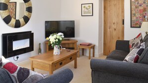 A living room with a TV, wooden furniture, a mirror, and a door.