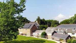 A rural setting with stone houses, a grassy field, and a large tree.
