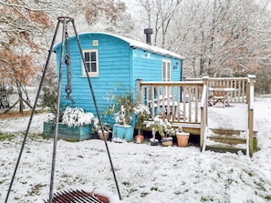 Ein blaues Holzhaus mit Veranda, umgeben von schneebedecktem Boden und Bäumen.