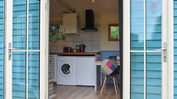A compact kitchen with a washing machine, a coffee maker, and a small table. - 1 bedroom accommodation in Herstmonceux, near Hailsham (Herstmonceux, near Hailsham)