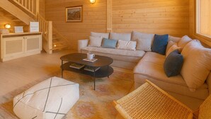 A cozy wooden cabin interior with a sofa, coffee table, and wicker furniture. - Cosy chalet with views of Mont Blanc (Chamonix-Mont-Blanc)