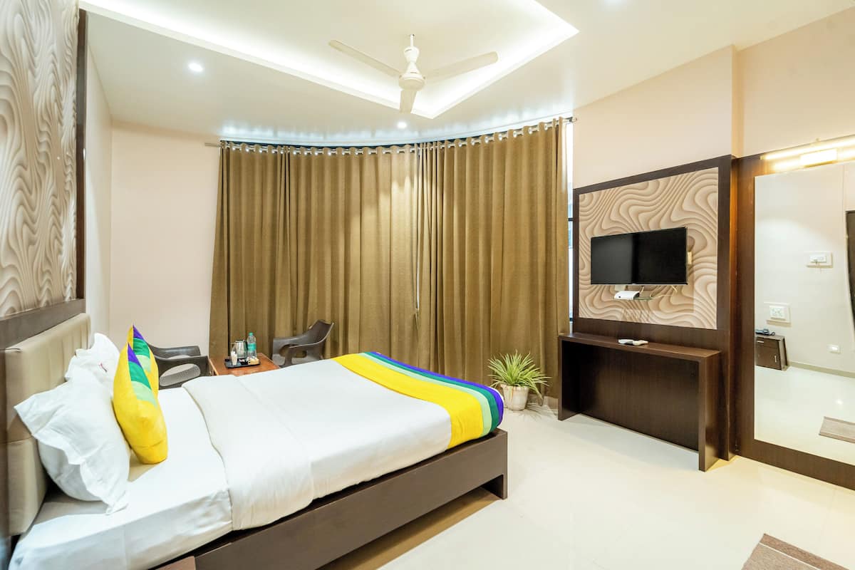 A modern hotel room with a bed, a desk, a chair, a television, and a ceiling fan.