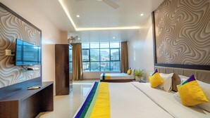 Una habitación de hotel moderna con una cama grande, un escritorio, un televisor de pantalla plana y vistas a la ciudad a través de amplios ventanales.