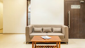 Un sofá de color neutro con dos almohadas y una mesa de centro de madera.