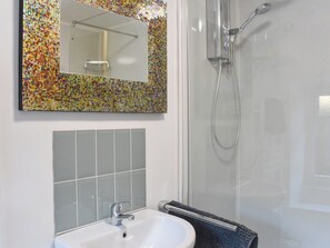Un baño con ducha, lavabo y espejo.
