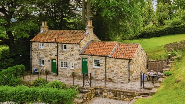 A stone building with a tiled roof, a paved entrance, and a small outdoor seating area. - Two bedroom cottage packed with character with stone floors and wood burner. (Hawnby, near Helmsley)