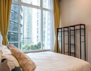 A bedroom with a bed, a window with curtains, and a metal shelf unit.