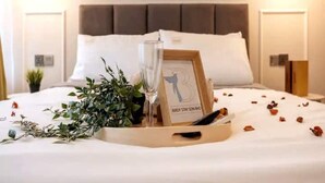 A neatly made bed with a framed picture, a glass of water, and scattered rose petals. - MONTLY OFFER 3BR 3 Min Walk KLCC FREE WIFI 6 PAX (Kuala Lumpur)