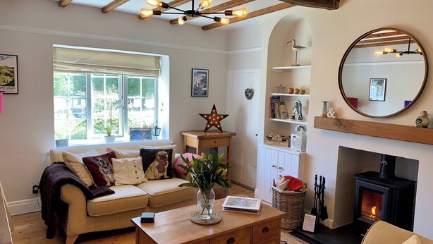 Una sala de estar acogedora con chimenea, techo de madera y un ventanal grande.