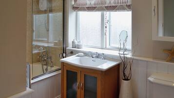 A bathroom with a bathtub, a sink, and a toilet. There is a window with a lace curtain and a starfish decoration.