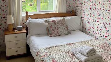 Una camera da letto con un letto, un comodino, una lampada e una finestra con tende.