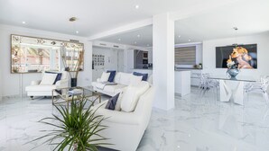 A modern living room with white sofas, a glass coffee table, and a large mirror. - Copacabana Deluxe 1-A  Levante Beach (Benidorm)