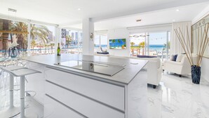 A modern kitchen with a large island, white cabinetry, and a view of the beach. - Copacabana Deluxe 1-A  Levante Beach (Benidorm)