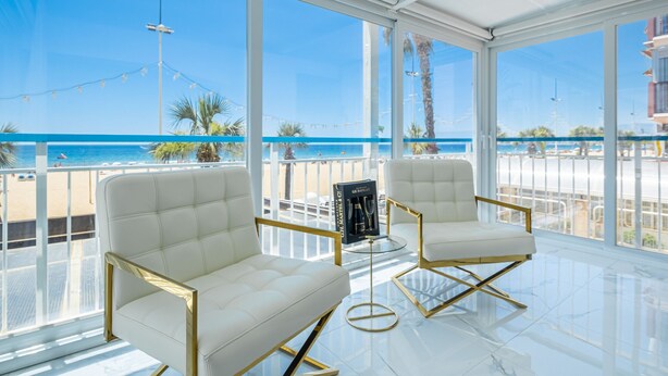 A spacious balcony with white leather chairs and a glass table, overlooking a beach and clear blue sky. - Copacabana Deluxe 1-A  Levante Beach (Benidorm)
