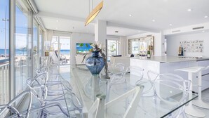 A modern kitchen with a large island, clear glass dining table, and chairs. - Copacabana Deluxe 1-A  Levante Beach (Benidorm)